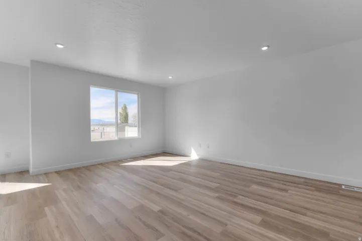 Wood-finish flooring with white walls, recessed ceiling lighting, and a large window
