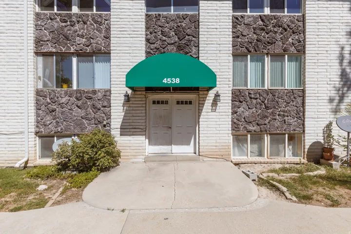 Building exterior with a green awning, white brick facade, and stone accents