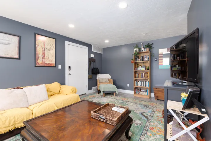 Recessed lighting, wood-finish flooring, white trim, and a white entry door