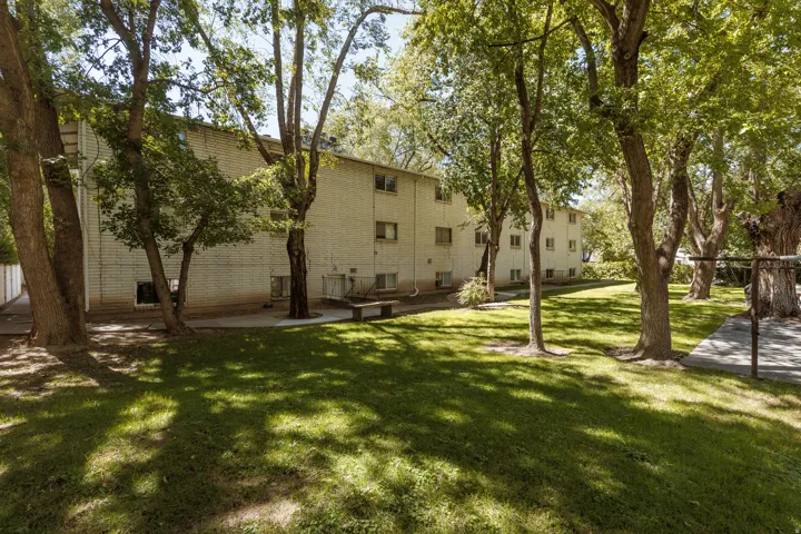 Manicured lawn with mature trees, brick exterior, and multi-story construction