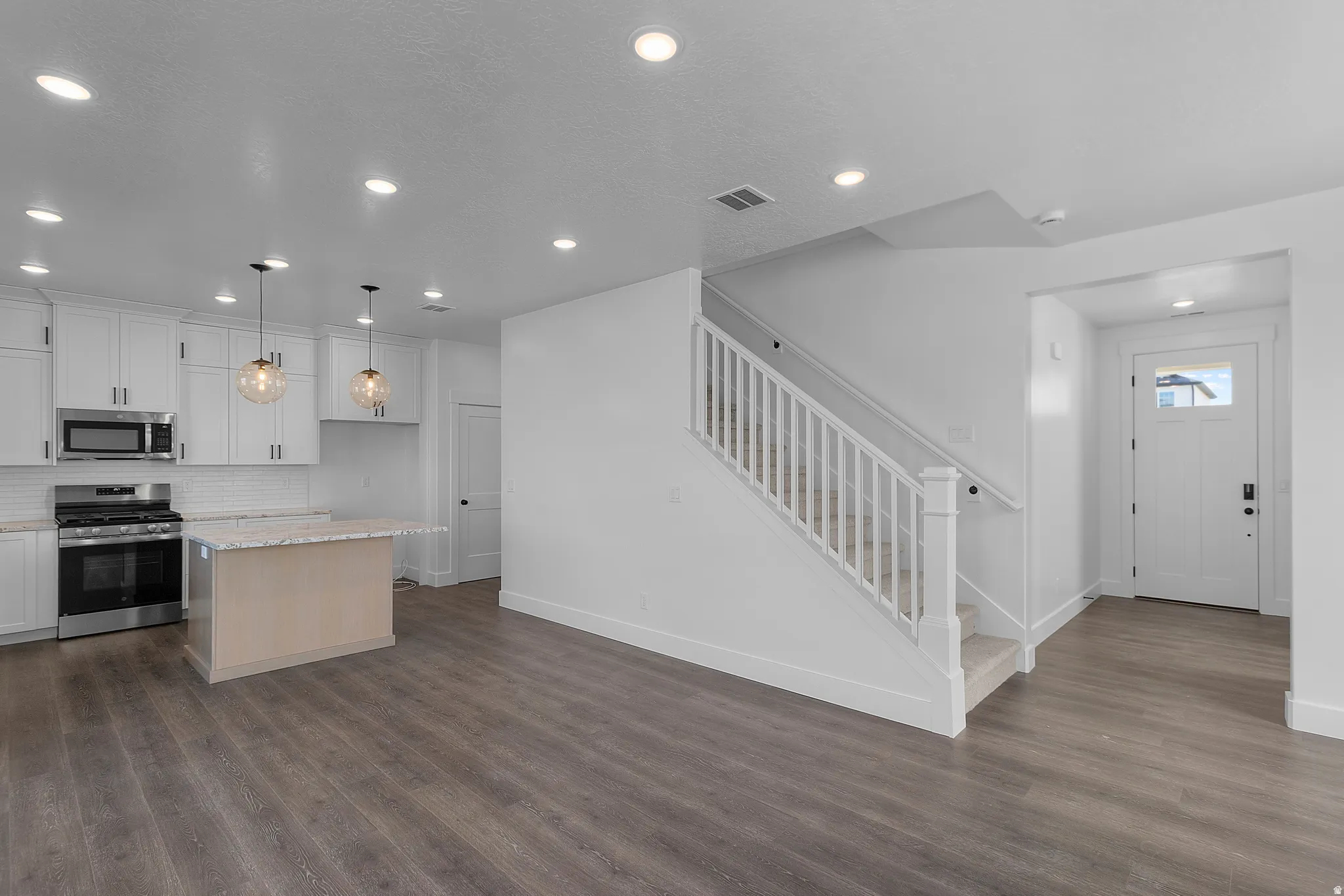 Modern kitchen featuring white cabinetry, stainless steel appliances, and a central island with a light-toned base
