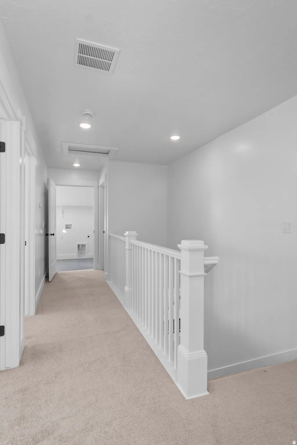 Carpeted hallway featuring recessed lighting and a white banister