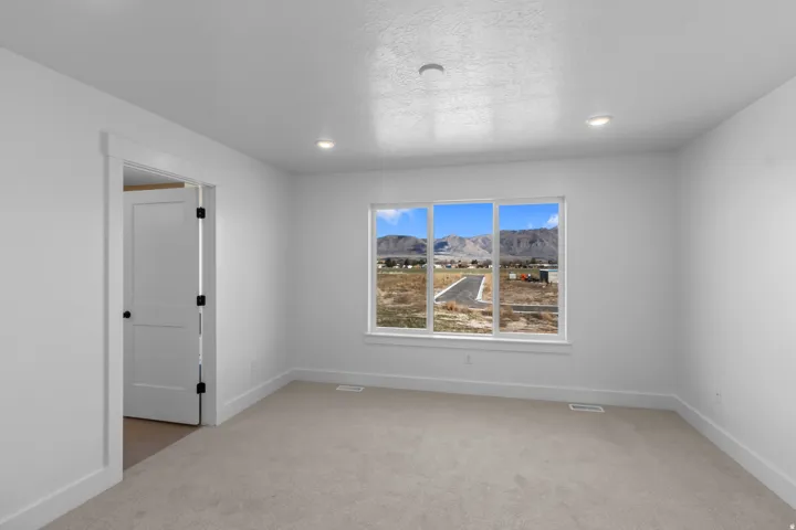 Recessed lighting, light-toned carpeting, white interior walls, white trim, and a white interior door with black hardware