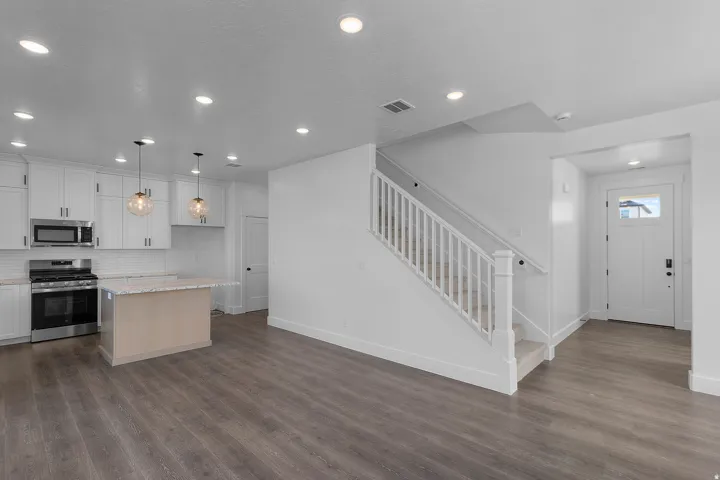 Modern kitchen featuring white cabinetry, stainless steel appliances, and a central island with a light-toned base