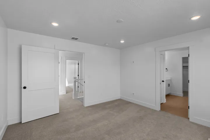 Recessed lighting, white trim and baseboards, neutral carpet flooring, and a white interior door with black hardware