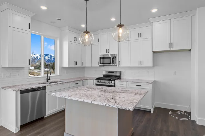 White shaker cabinetry, stainless steel appliances, granite countertops, and wood-finish flooring