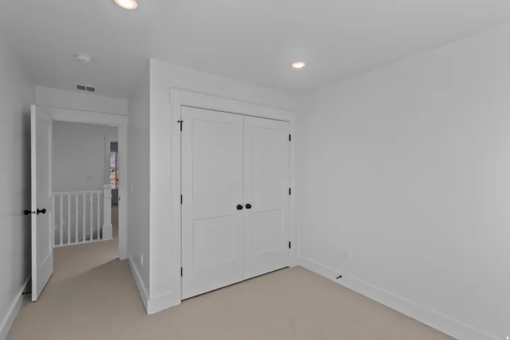 Neutral tone wall paint, recessed ceiling lighting, two-panel closet doors with dark hardware, and plush carpet flooring