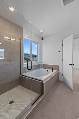 Glass-enclosed shower with mosaic tile flooring, a built-in bathtub with a dark-finish faucet, and coordinating wall and floor tiles
