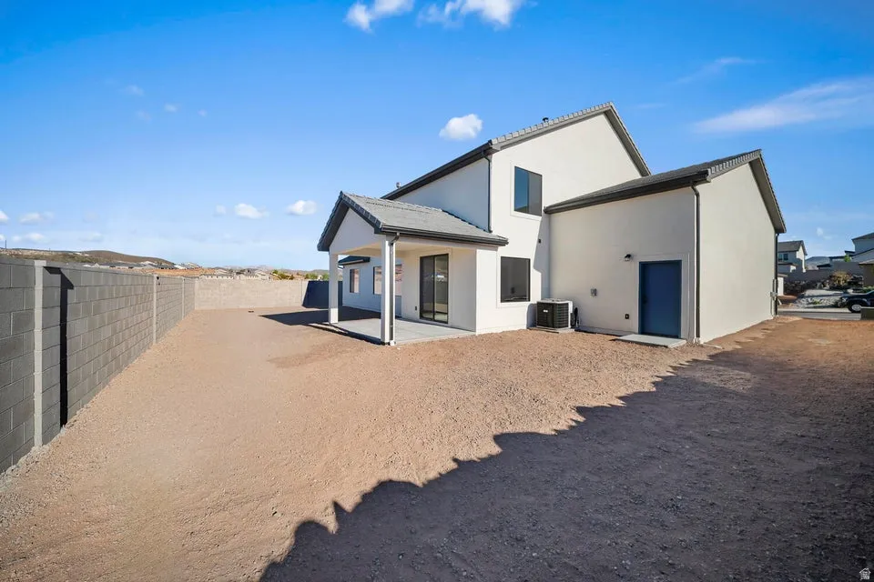 Modern stucco exterior with a covered patio, dark framed windows, and a blue exterior door