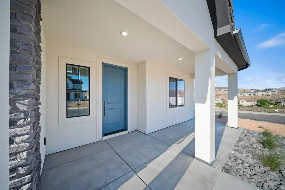 Covered front porch with a paneled blue door, stone facade accent, and black-framed windows