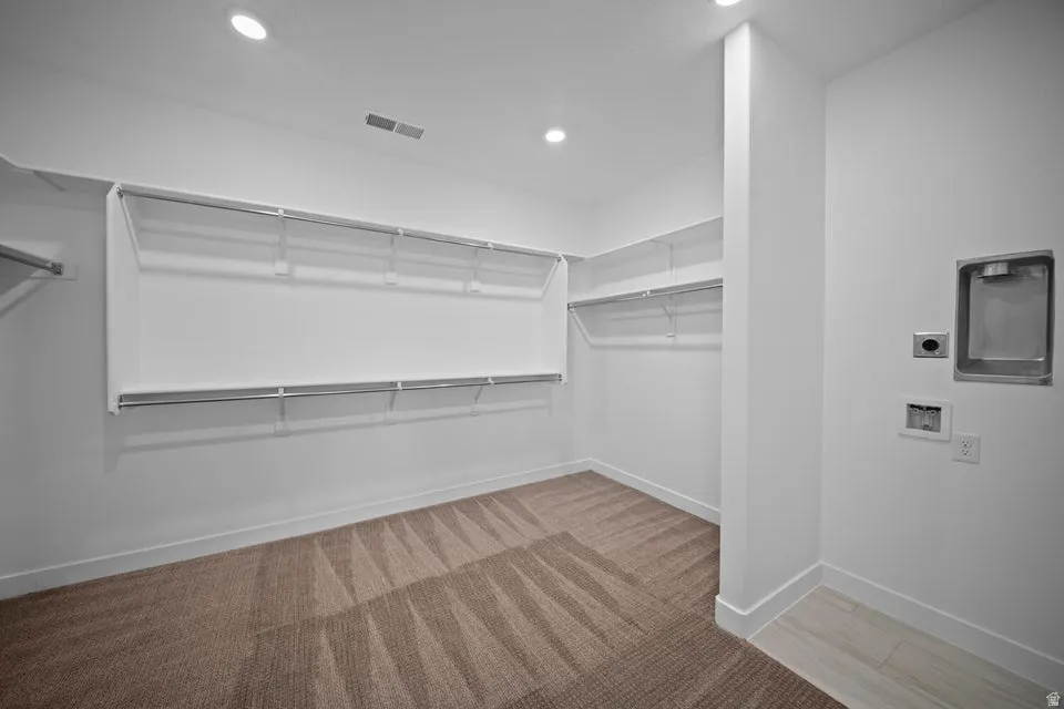 Spacious closet with wire shelving and clothes rods, complemented by recessed lighting and a laundry appliance hookup
