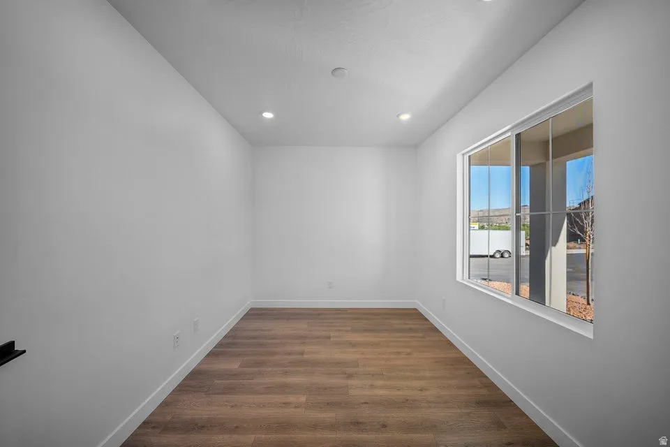 Recessed lighting, large window, wood-finish flooring, white walls, and white trim
