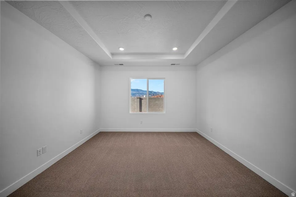 Bright, light-filled bedroom with recessed ceiling lighting, clean white walls, and neutral wood-finish flooring