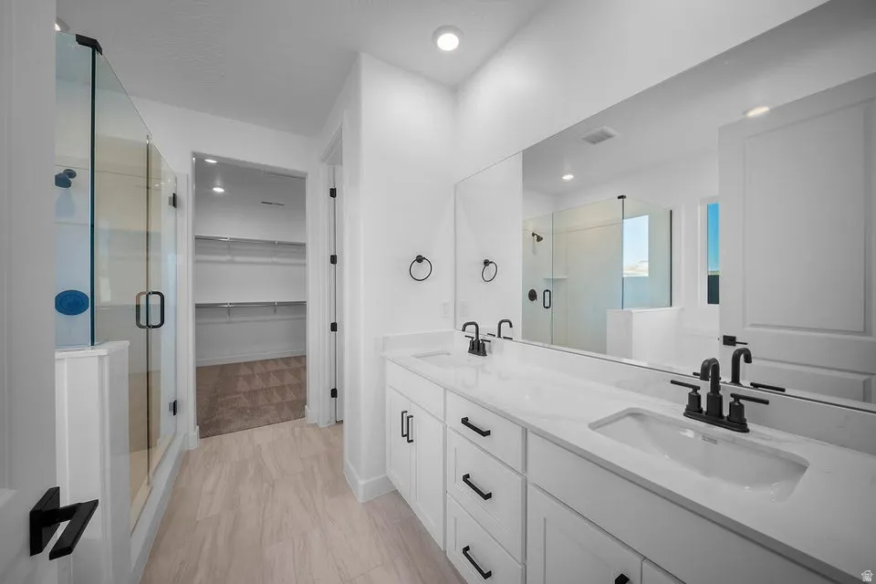 Dual vanity with white cabinetry, matte black hardware, and an expansive mirror