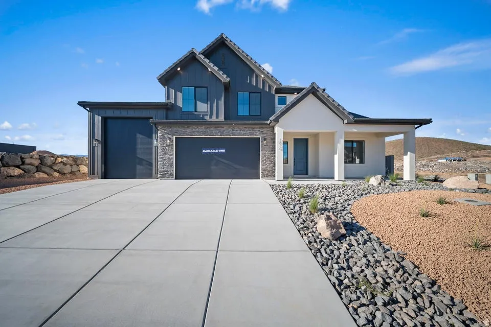 Modern exterior with dark vertical siding, stone accents, a covered entry, and a multi-car garage