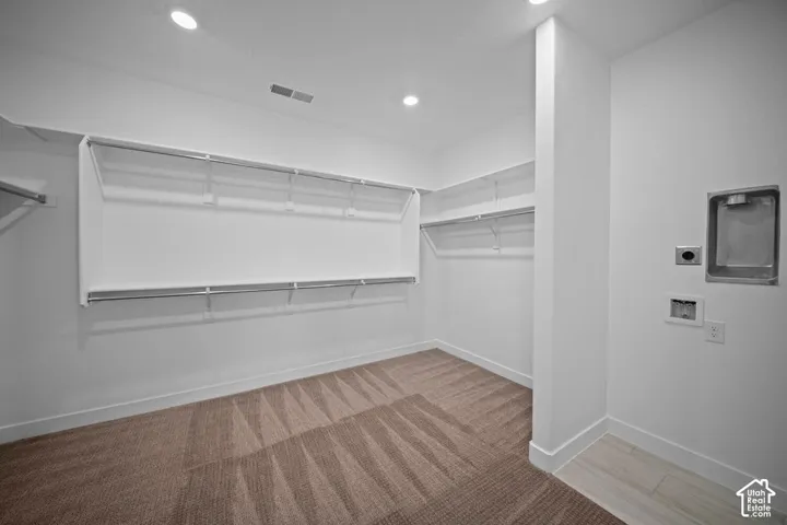 Spacious closet with wire shelving and clothes rods, complemented by recessed lighting and a laundry appliance hookup