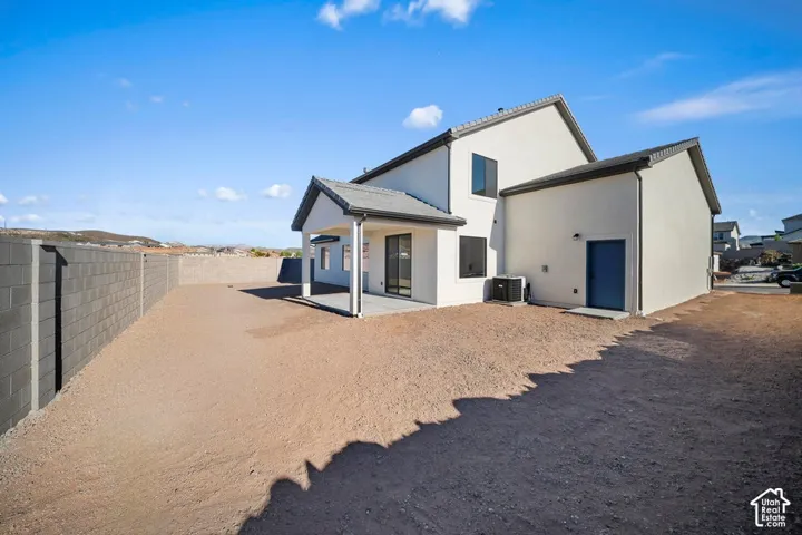 Modern stucco exterior with a covered patio, dark framed windows, and a blue exterior door