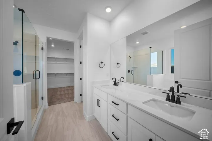 Dual vanity with white cabinetry, matte black hardware, and an expansive mirror