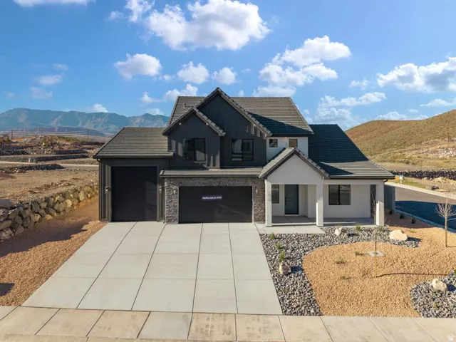 Contemporary exterior with dark siding and light stucco accents, multiple garages, an inviting covered entry, and a mountain backdrop