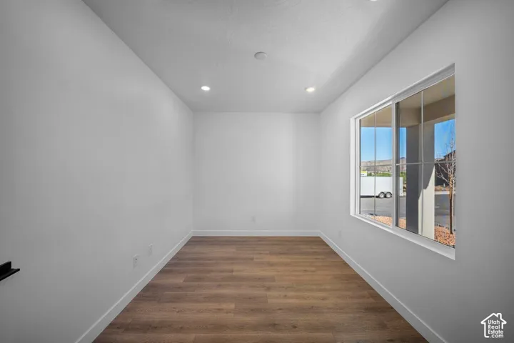 Recessed lighting, large window, wood-finish flooring, white walls, and white trim