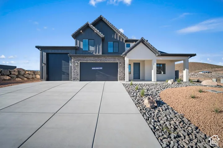 Modern exterior with dark vertical siding, stone accents, a covered entry, and a multi-car garage