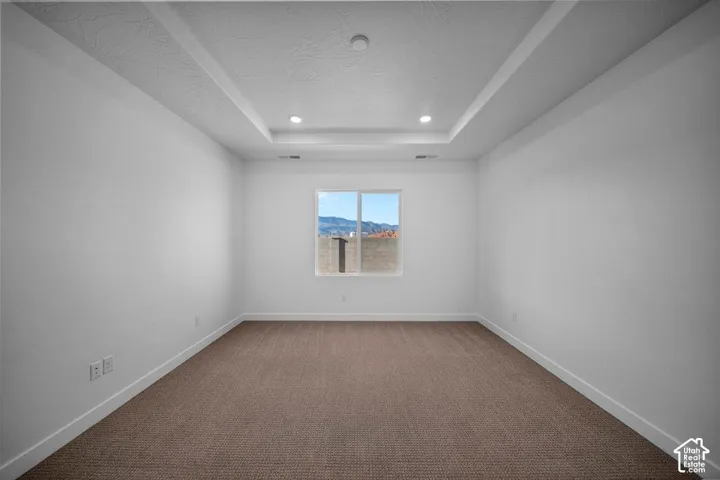 Bright, light-filled bedroom with recessed ceiling lighting, clean white walls, and neutral wood-finish flooring