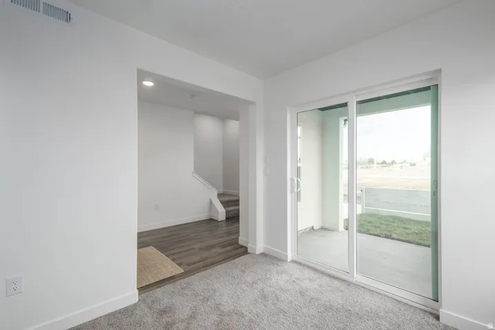 Sliding glass patio door with white frame, light gray carpeting, wood-finish flooring, and recessed ceiling lighting