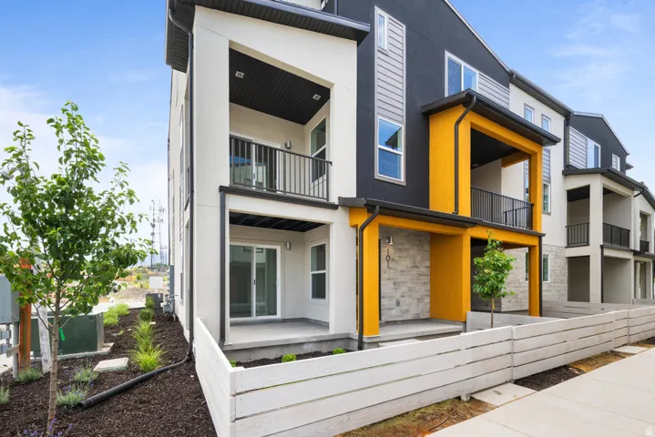 Modern facade with horizontal siding accents, stone veneer detailing, covered entry, and upper-level balcony