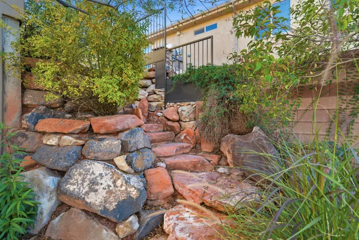 Stone retaining wall with integrated stepping stones leading to a wrought iron gate