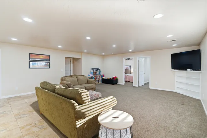 Recessed lighting illuminating a spacious room with mixed flooring, including carpet and large format tiles