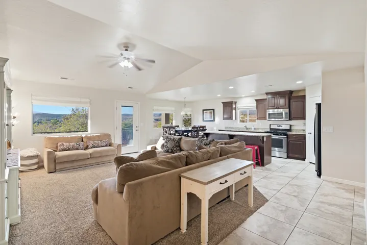 Open-concept living space with vaulted ceilings, a ceiling fan, and large windows
