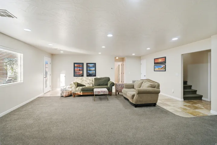 Spacious interior with recessed lighting, carpet flooring, window with blinds, and a door with a glass panel