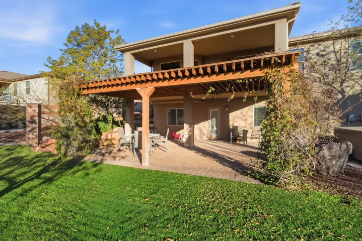 Expansive backyard featuring a manicured lawn, a large paver patio, and a wood pergola