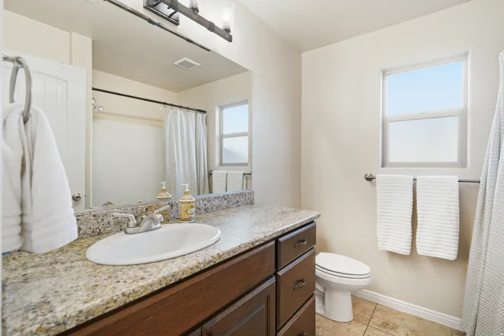 Vanity with granite-style countertop, integrated sink, and dark wood-finish cabinetry