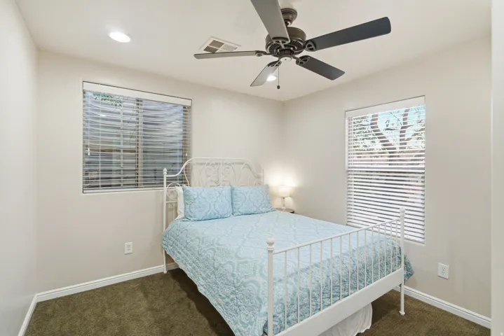 Recessed ceiling lighting, ceiling fan, and two windows with horizontal blinds