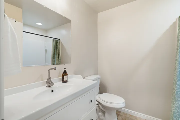 White vanity with integrated sink, brushed nickel faucet, large wall mirror, and toilet