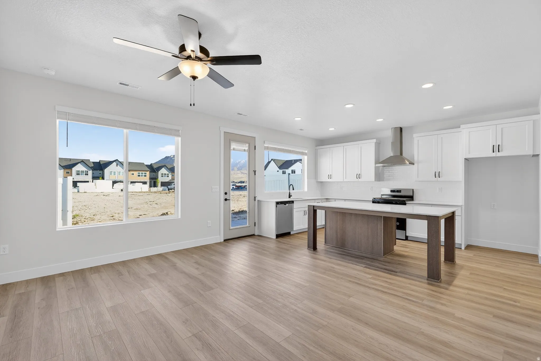 Open-concept living space with wood-finish flooring, recessed lighting, and a ceiling fan