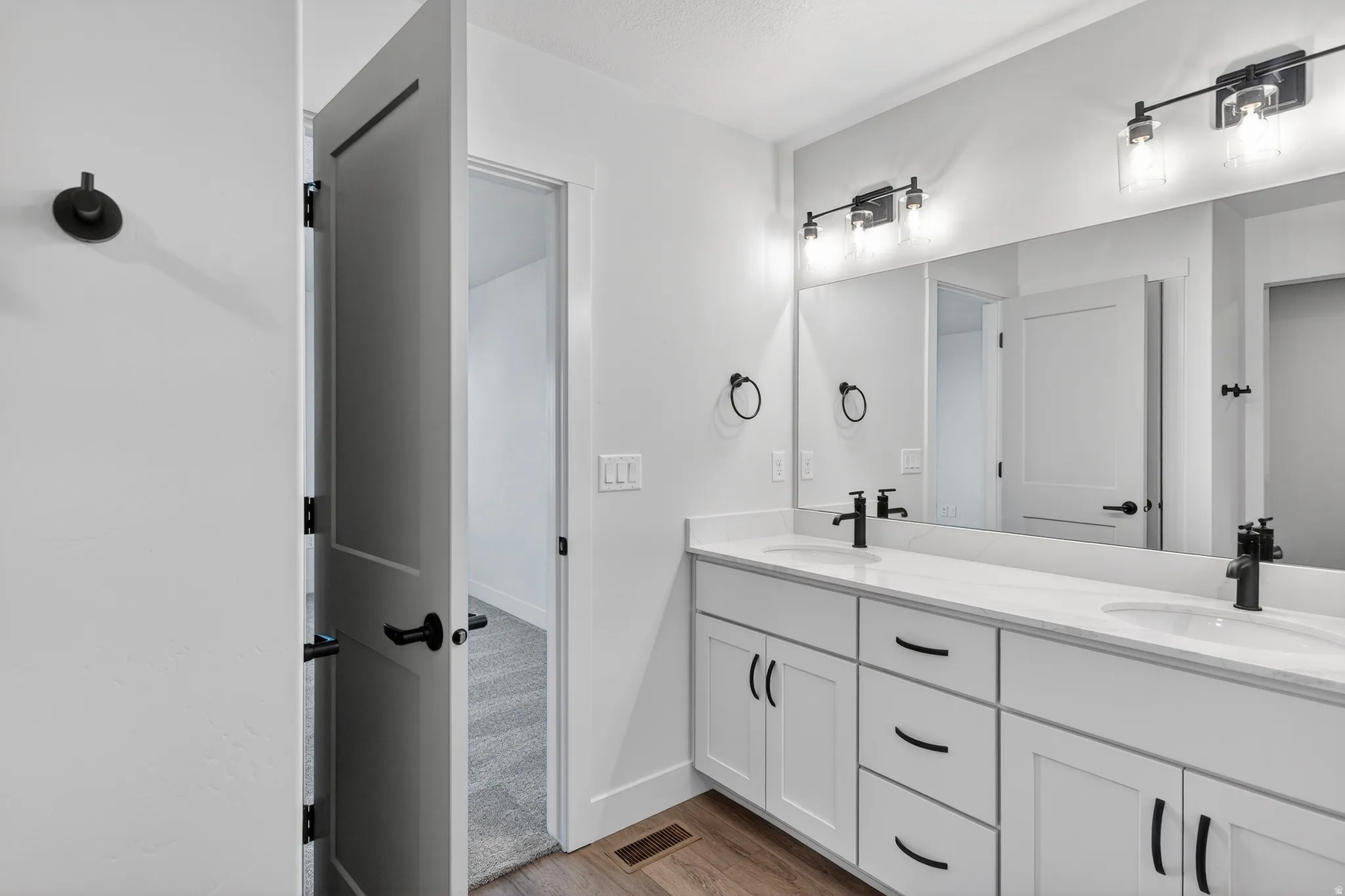 Dual vanity with integrated sinks, white cabinetry, and matte black hardware