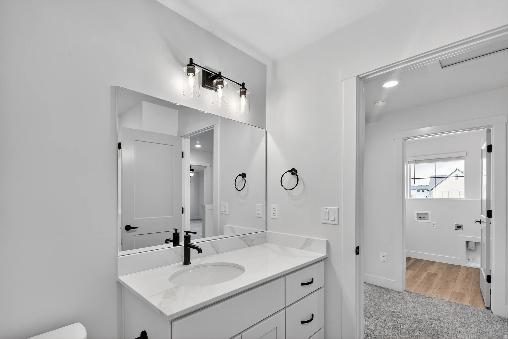 White vanity with black hardware, rectangular undermount sink, and quartz countertop