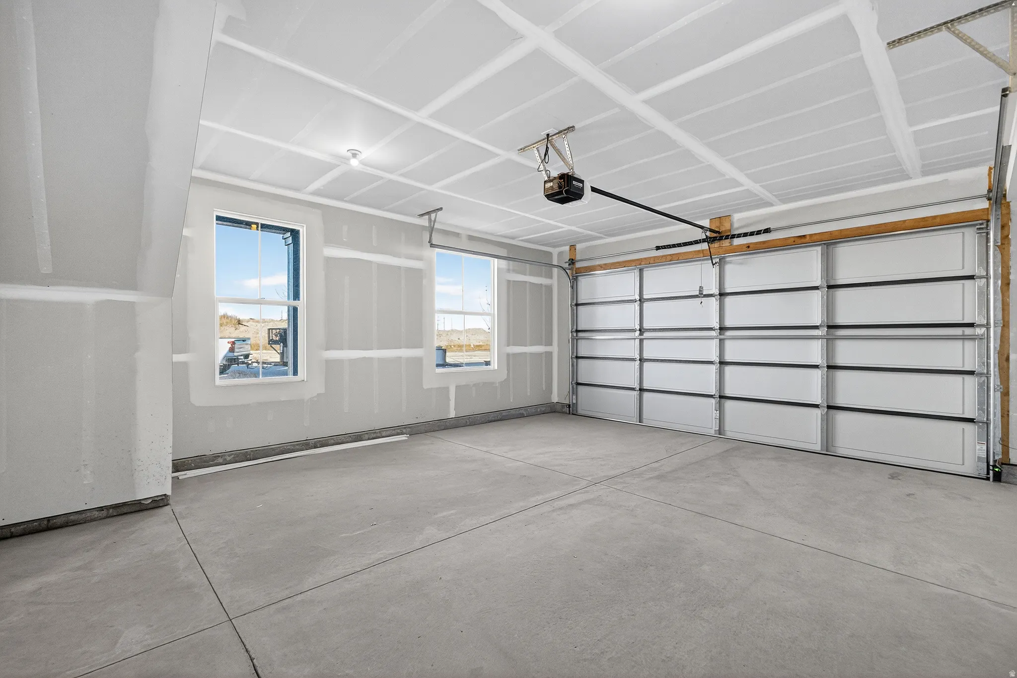 Spacious garage featuring a concrete floor, two windows, and an overhead garage door with an automatic opener