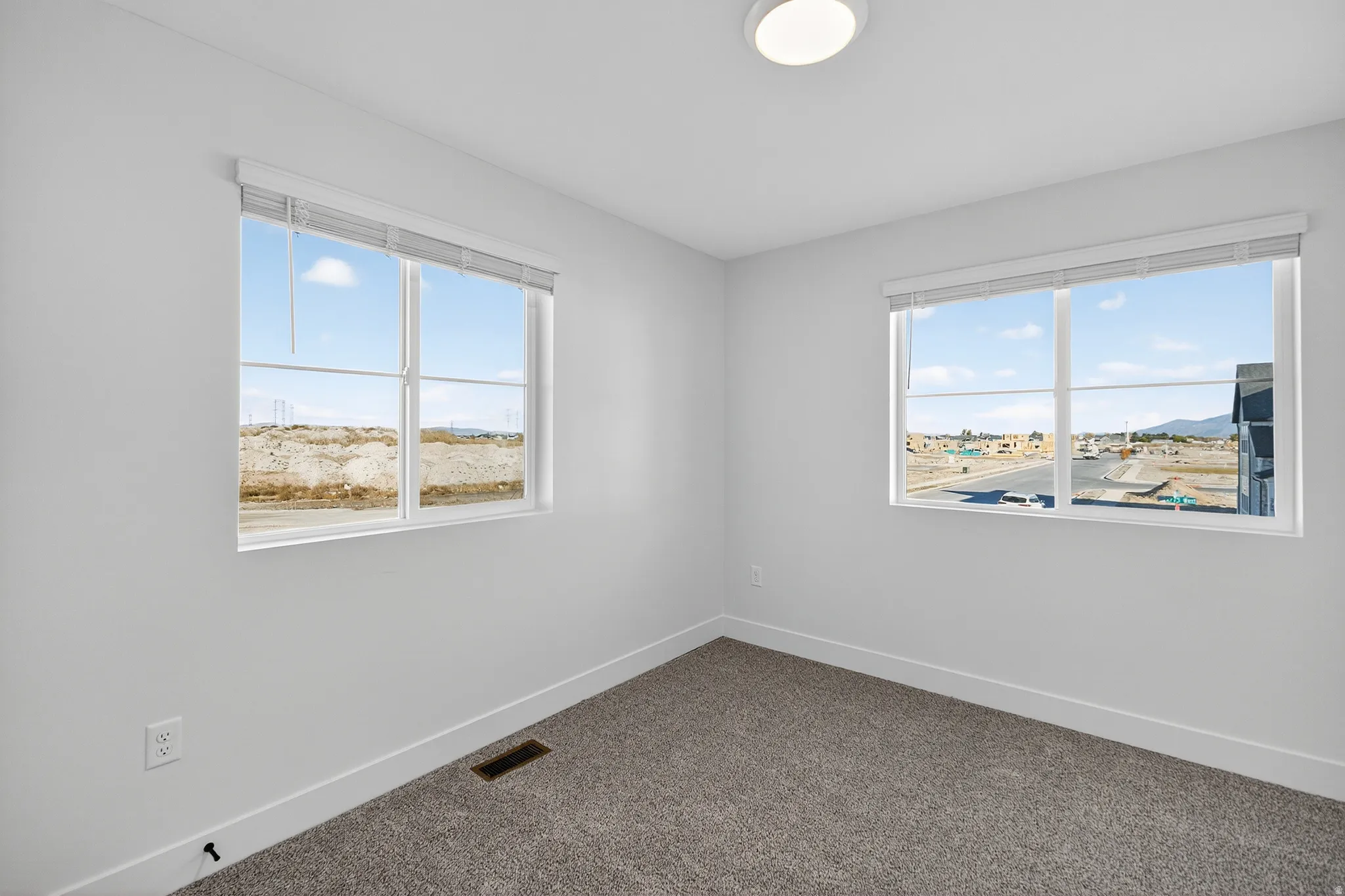 White walls, neutral carpeting, and two bright windows