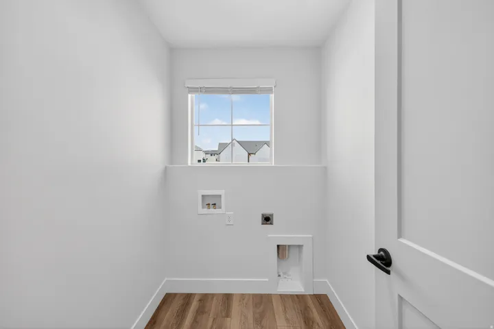 Built-in utility connections, wood-finish flooring, white trim, and a window