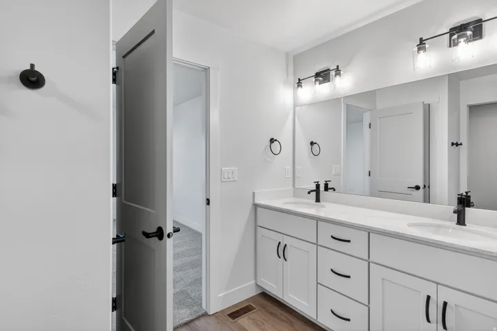 Dual vanity with integrated sinks, white cabinetry, and matte black hardware