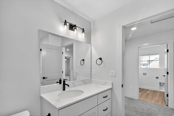 White vanity with black hardware, rectangular undermount sink, and quartz countertop