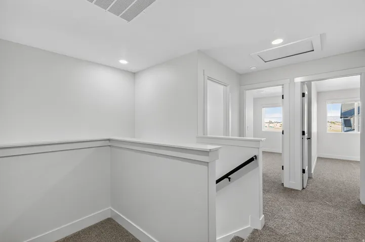 Carpeted hallway with white walls and trim, recessed lighting, and white paneled doors