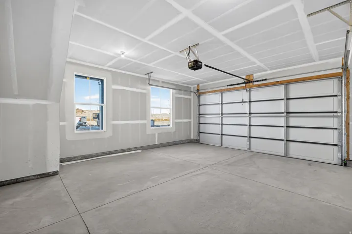 Spacious garage featuring a concrete floor, two windows, and an overhead garage door with an automatic opener
