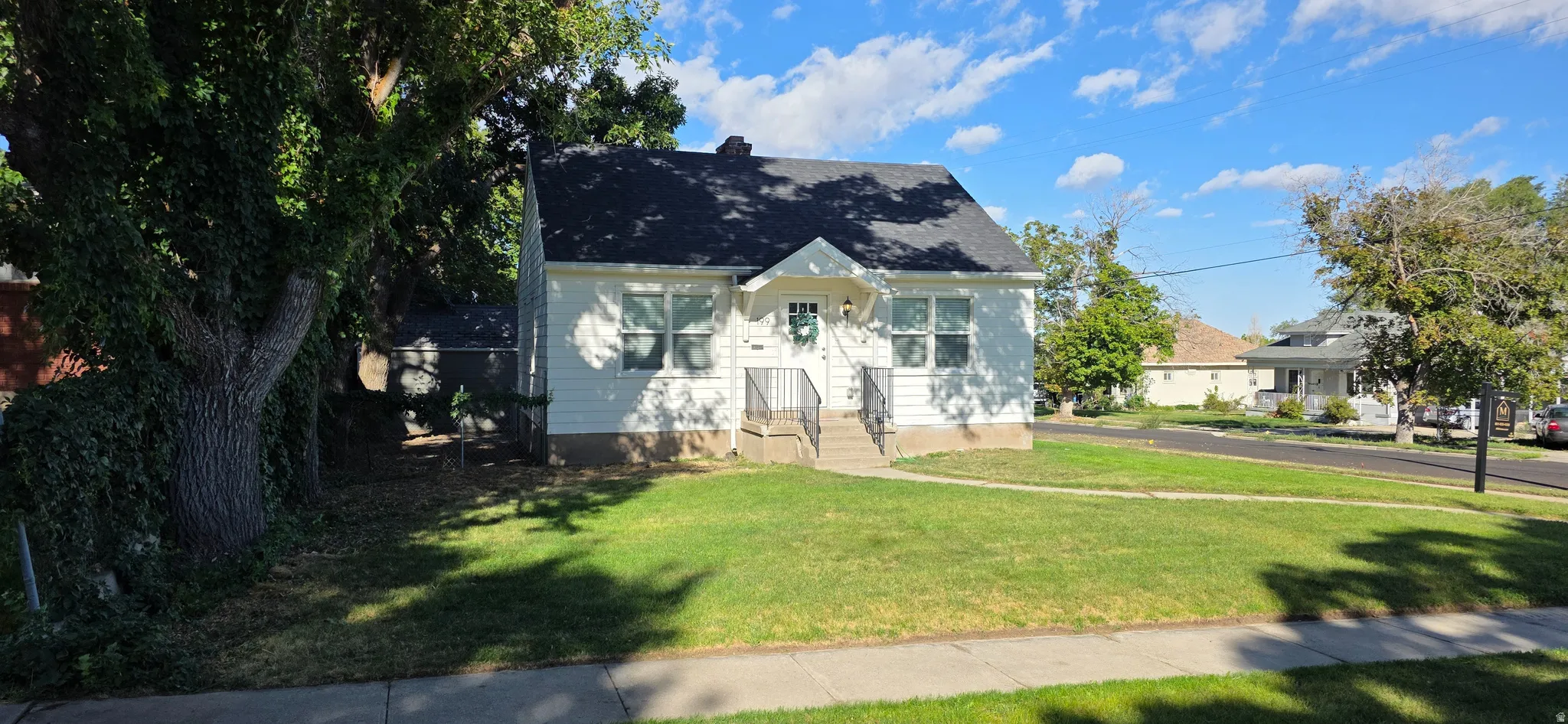 White exterior with a dark shingle roof and front porch