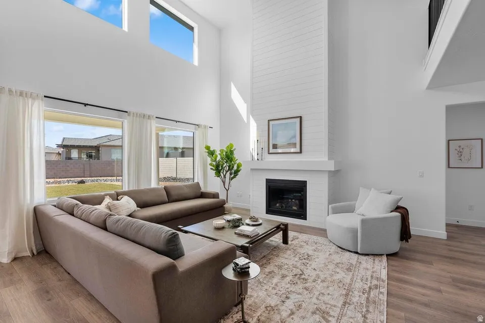 Wood-finish flooring throughout, paired with a floor-to-ceiling fireplace featuring a white shiplap-style finish