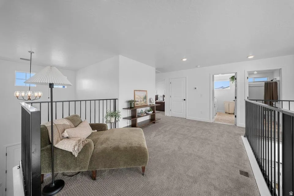 Spacious carpeted landing featuring black metal railings, recessed lighting, and white interior doors