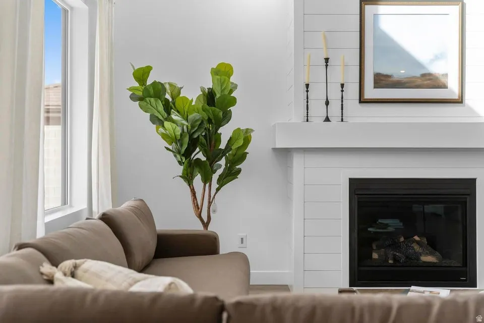 Living area featuring a modern fireplace with a shiplap surround, white mantel, and a large window with white curtain panels